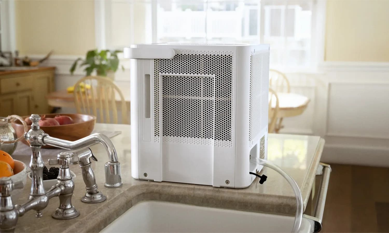 Midea Cube dehumidifier positioned beside a sink with a drain hose attached