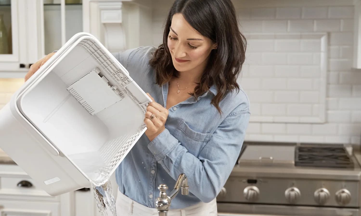 Person emptying the large removable bucket from a Midea Cube dehumidifier