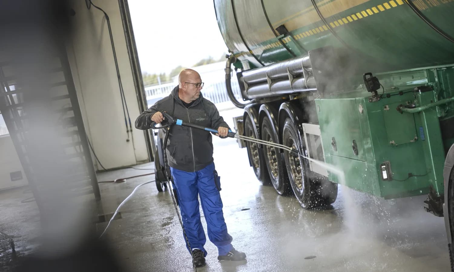 Operator pressure washing a commercial tanker vehicle