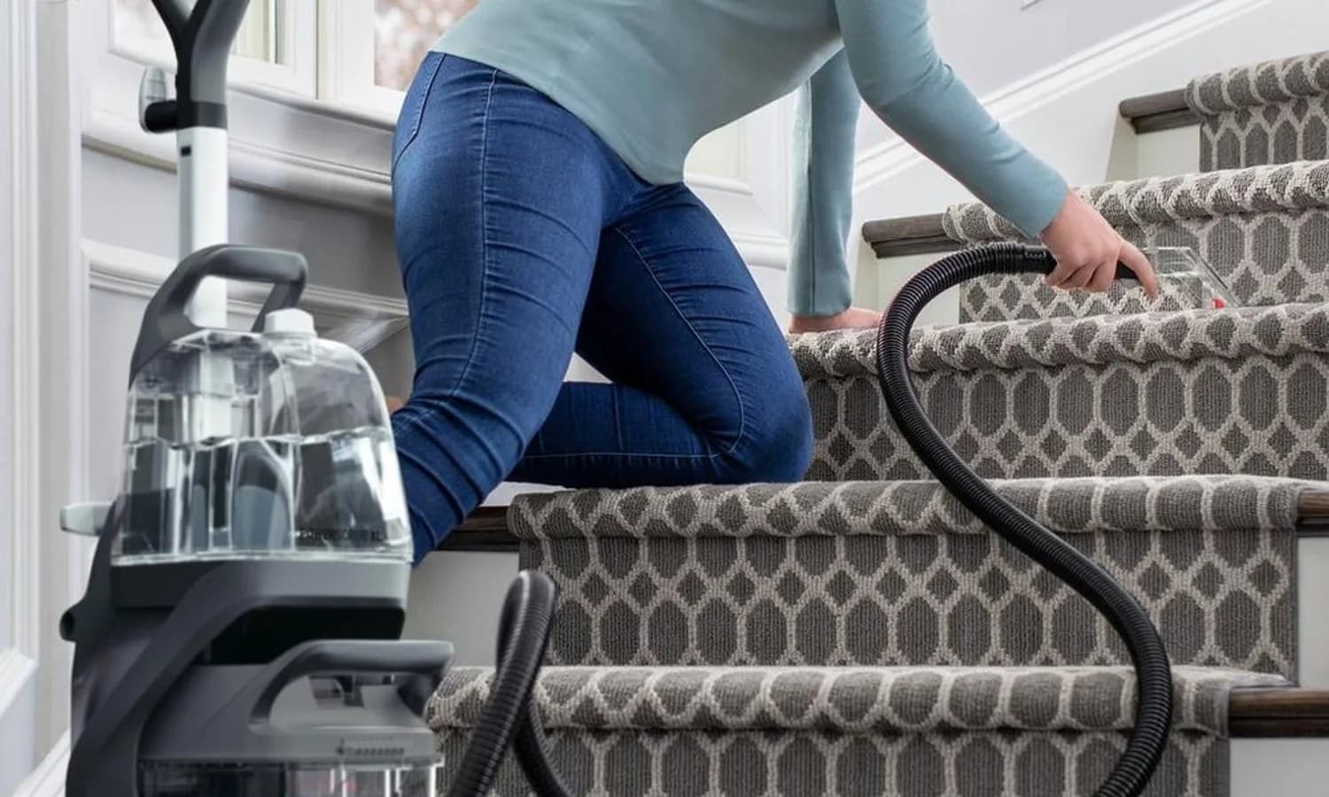Person using a Hoover carpet cleaner hose tool on carpeted stairs