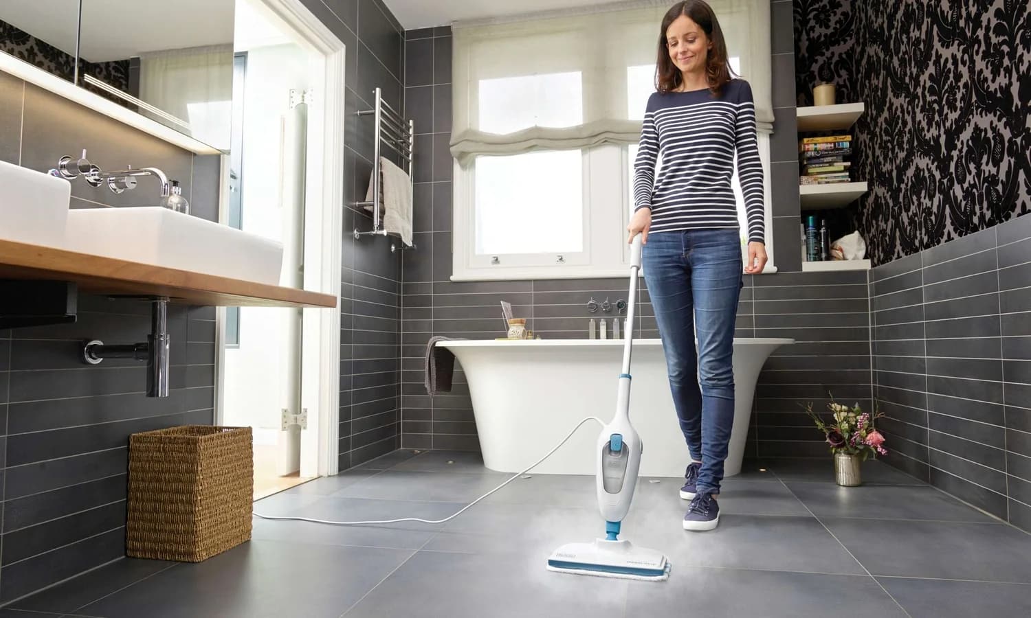 Person operating a BLACK+DECKER steam mop on a tiled bathroom floor