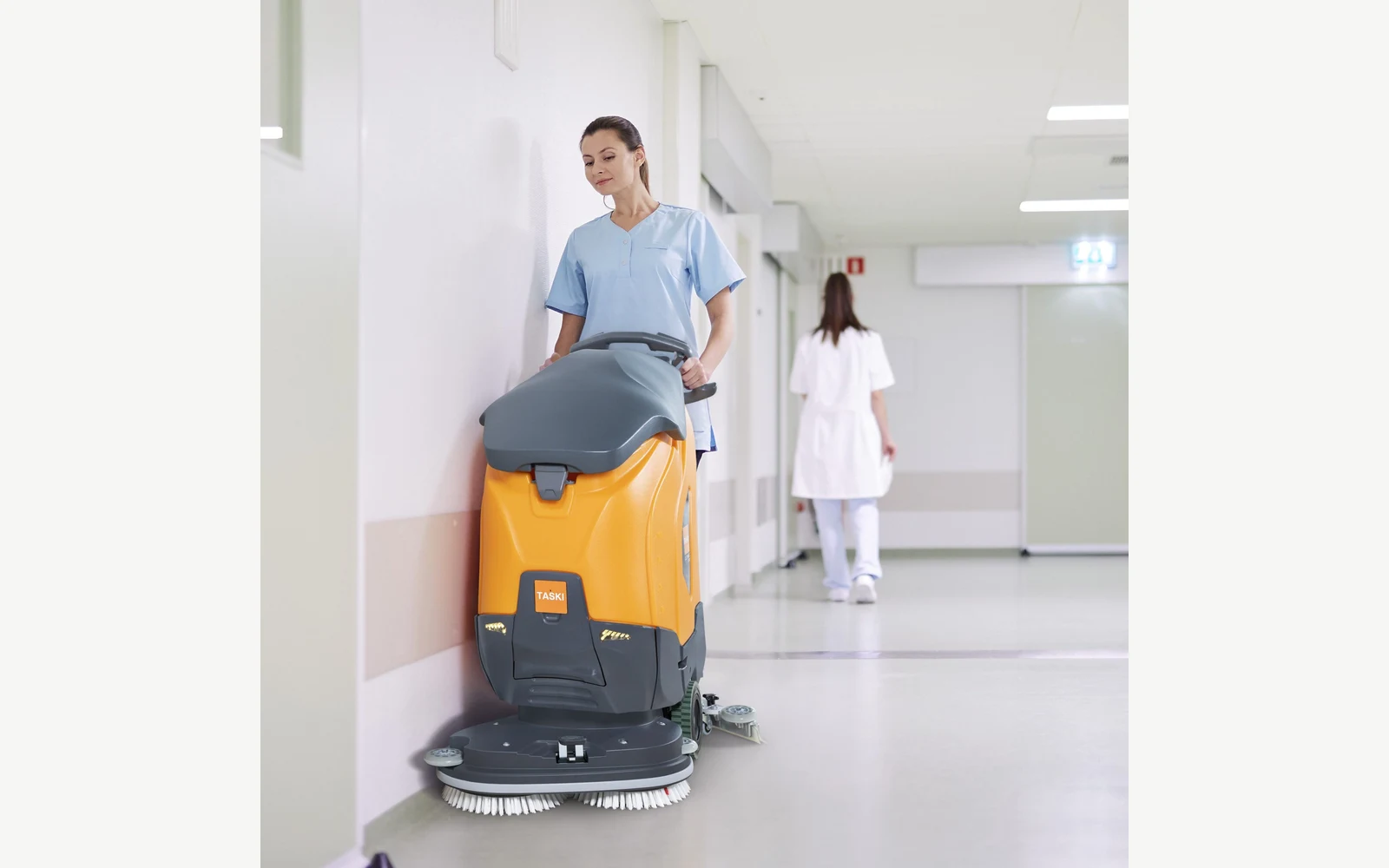 Operator using a TASKI ULTIMAXX floor scrubber in a healthcare corridor