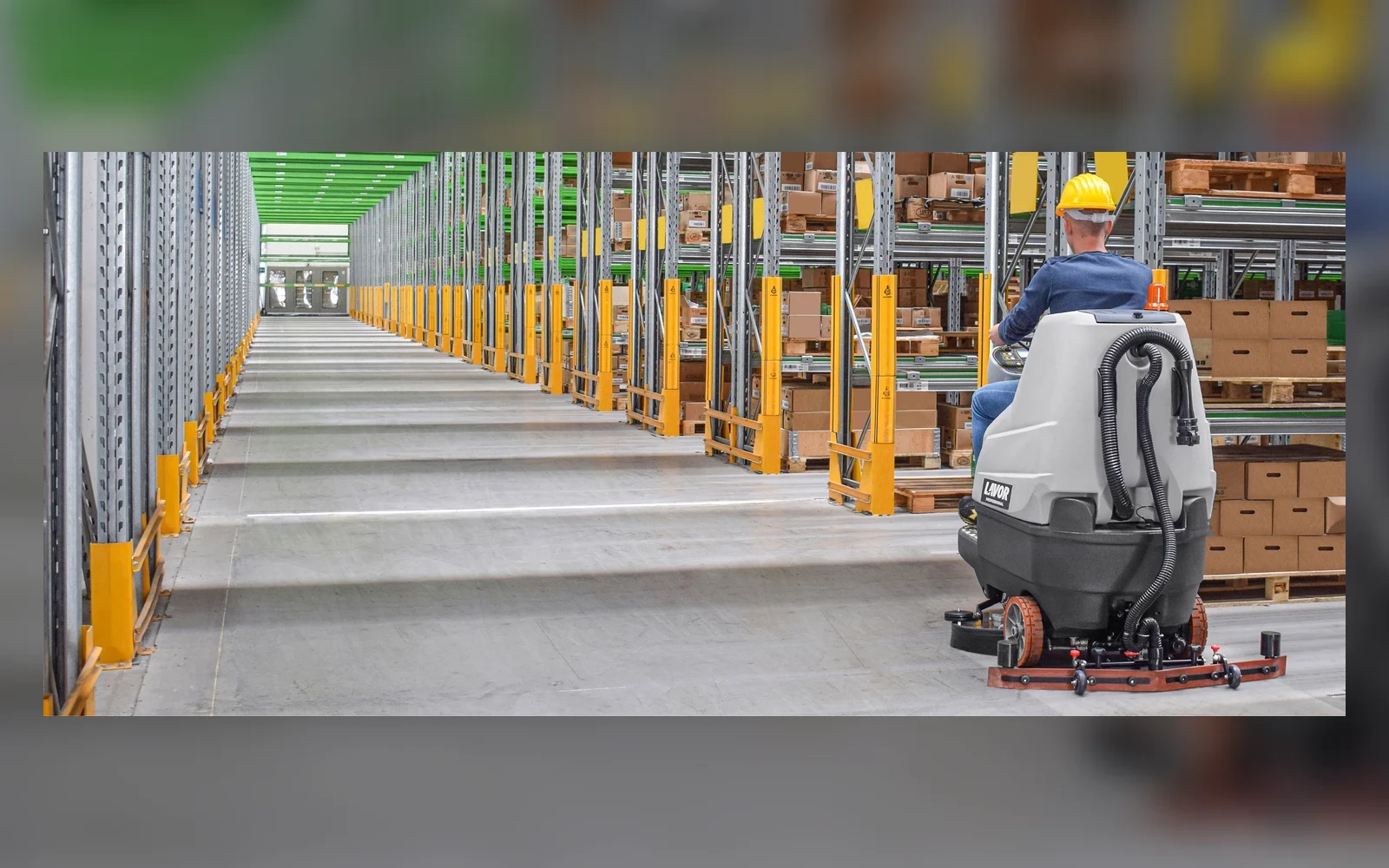 Lavor professional ride-on floor scrubber operating in a warehouse